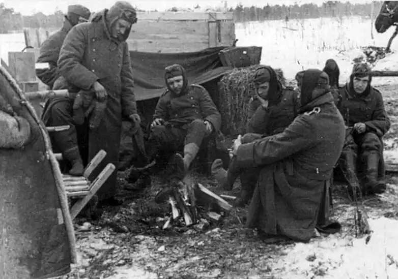 German prisoners of war warming themselves and drying their boots beside a campfire in a Soviet prisoner-of-war camp, spring 1943.