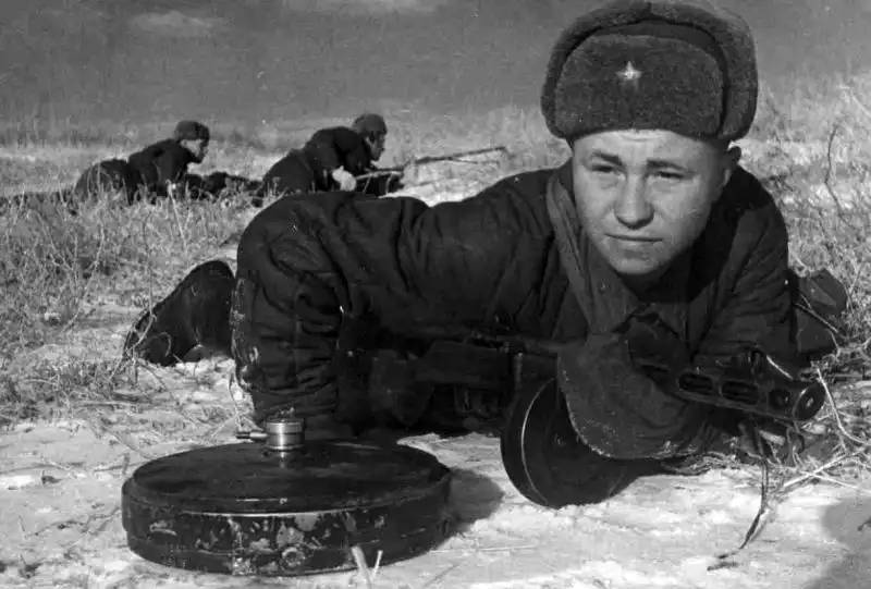 Soviet sapper Nikolai Zakharov lying in the snow with a PPSh-41 next to a German Tellermine 35 anti-tank mine near Stalingrad in November 1942.