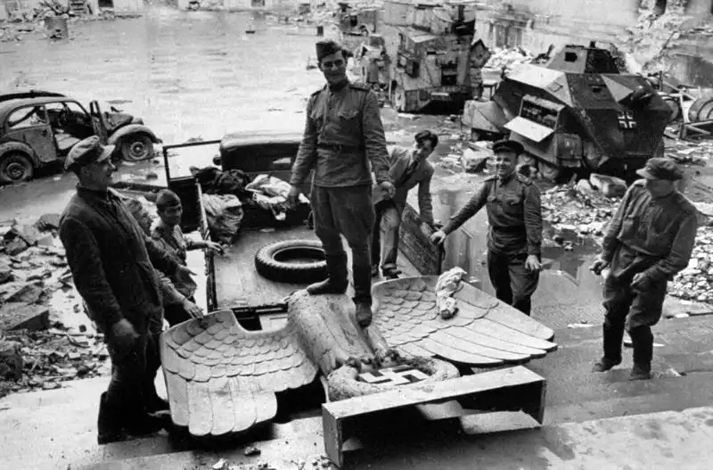 Historical photo by William Vandivert of Soviet soldiers standing on a bronze Nazi eagle loaded onto a truck in the ruined courtyard of the Berlin Reich Chancellery in 1945.