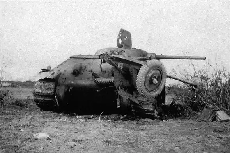 Early model Soviet T-34 tank resting on top of a crushed German 3.7 cm PaK 35/36 anti-tank gun in a field in the Baltic states, summer 1941.