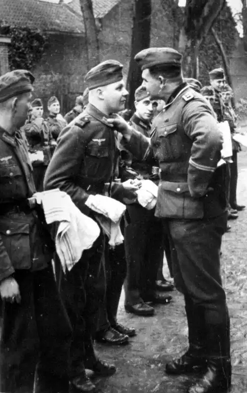 German Wehrmacht Hauptfeldwebel inspecting the collar and uniform of a young soldier holding a towel during morning inspection 1938.