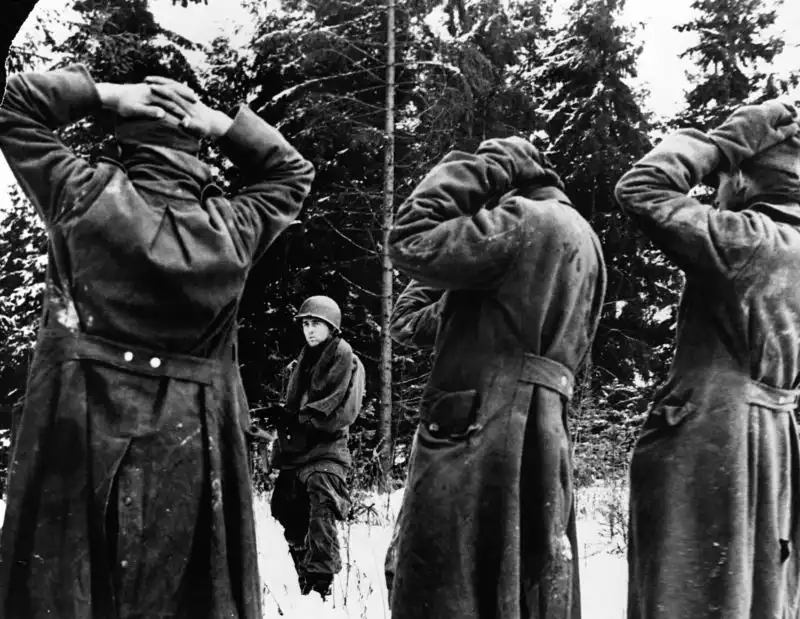 German prisoners of war guarded by an American soldier during the Battle of the Bulge in Belgium, January 1945.