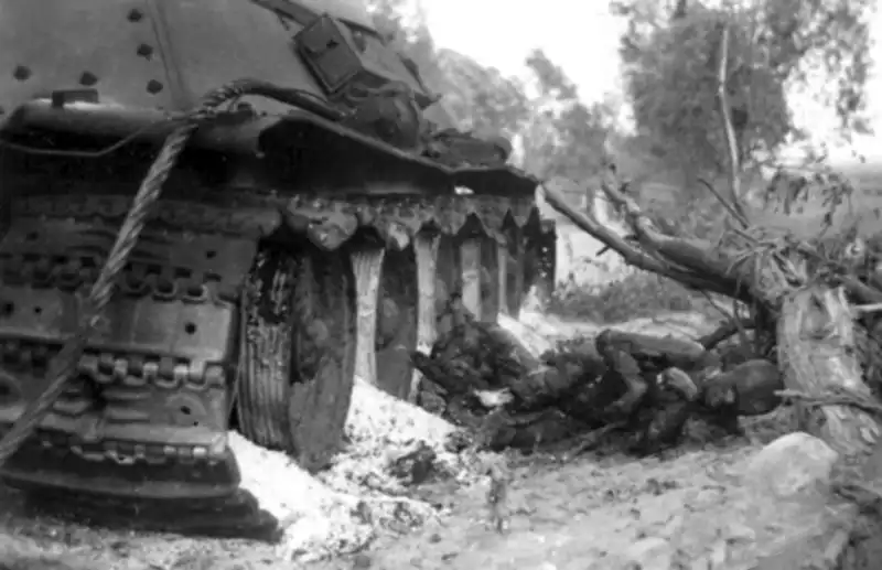 Knocked-out Soviet T-34 Model 1941 tank with towing cable and damaged tracks in a roadside ditch summer 1941.