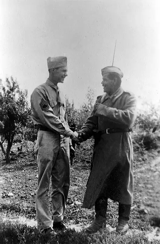Soviet infantryman shakes hands with US Sergeant Bernard McGuire at Poltava airfield, Ukraine, June 1944, during Allied shuttle bombing operations in WWII.