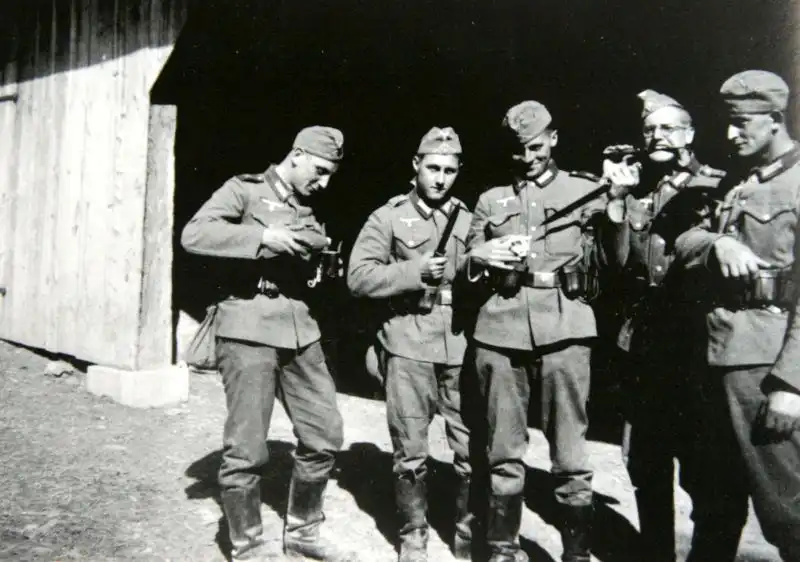 German Wehrmacht soldiers in garrison uniform posing with a small kitten and Seitengewehr 84/98 bayonets 1940.