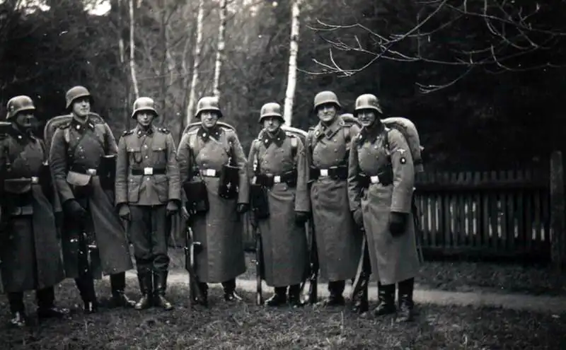 Group of pre-war SS soldiers wearing M36 greatcoats armed with Erma EMP 35 submachine guns with wooden foregrips and early leather magazine pouches in 1938 Germany.
