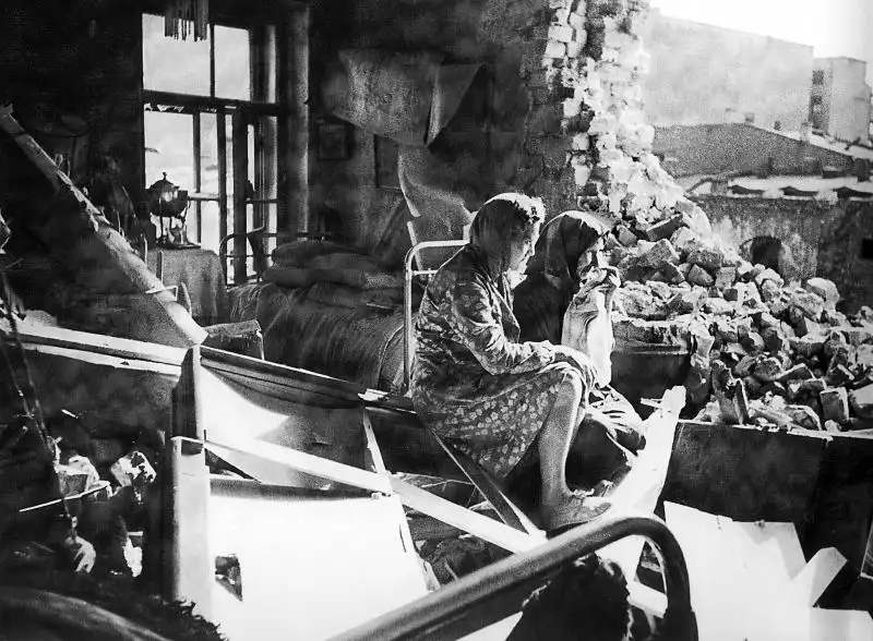 Soviet women Anisya Amelkina and her daughter Valentina sitting in a Leningrad apartment destroyed by German artillery shelling during the Siege of Leningrad, spring 1943