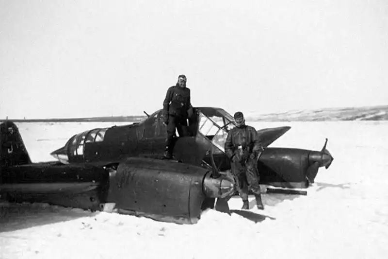 German Luftwaffe crew standing next to a Focke-Wulf Fw 189 Uhu twin-boom reconnaissance plane resting on its belly in deep snow, winter 1942.