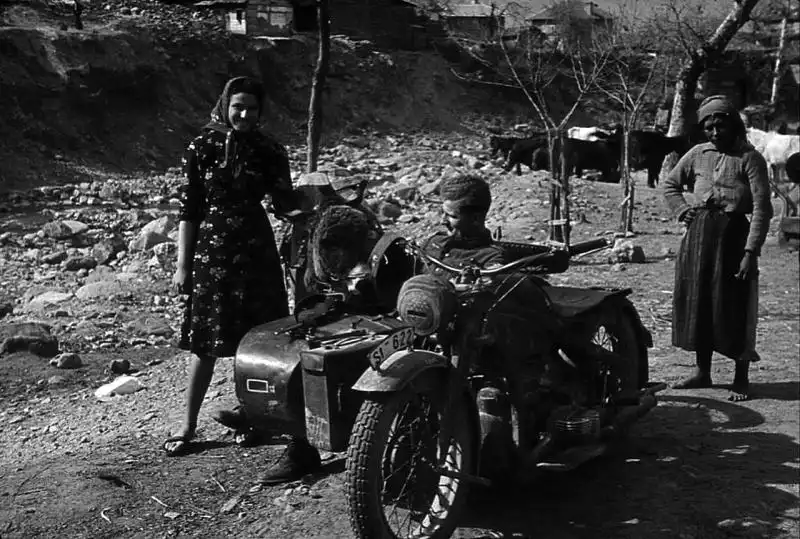 German Wehrmacht motorcycle dispatch rider on a Zündapp KS 500 with sidecar talking to Bulgarian peasant women in the countryside during the Balkan Campaign, spring 1941