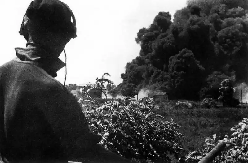 German Pz.Kpfw. III tank crewman wearing headset observing dense black smoke from burning oil storage tanks in Maikop August 1942.