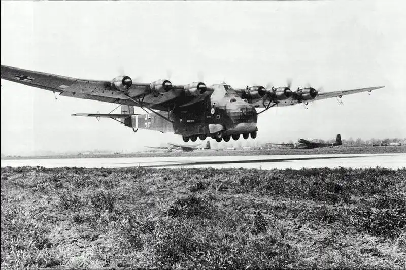 Black and white historical photo of a giant six-engine German Messerschmitt Me 323 Gigant transport plane taking off from an airfield.
