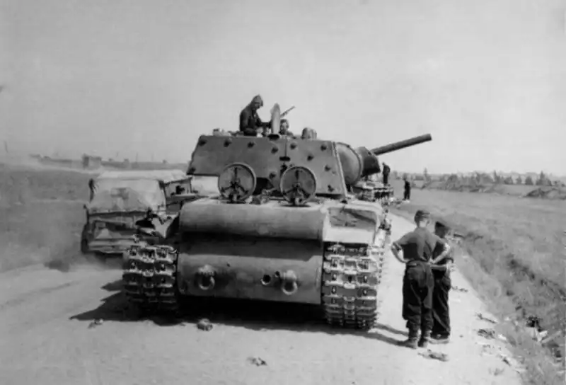 Captured Soviet KV-1 heavy tanks lie destroyed or abandoned along a dirt road