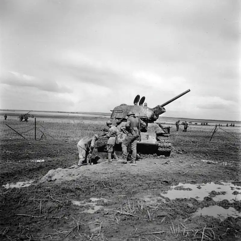 Soviet POWs digging a grave under German guard beside a destroyed T-34 Model 1942 tank on the Mius-Front in August 1943.