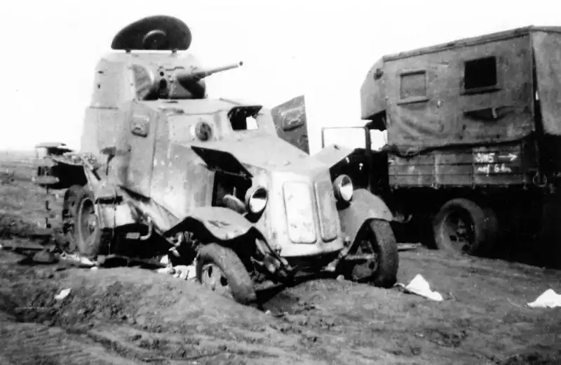 Abandoned Soviet BA-10 armored car with open engine hatches beside a PARM-1A mobile repair workshop during the Red Army retreat, USSR, August 1941.