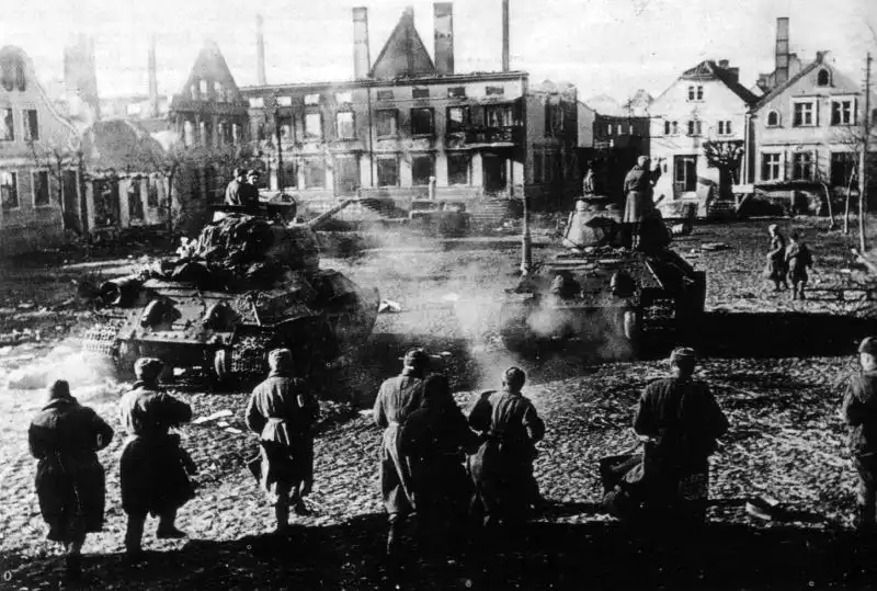 Red Army T-34-85 tanks and infantry advancing through damaged streets of Frauenburg in East Prussia during February 1945.