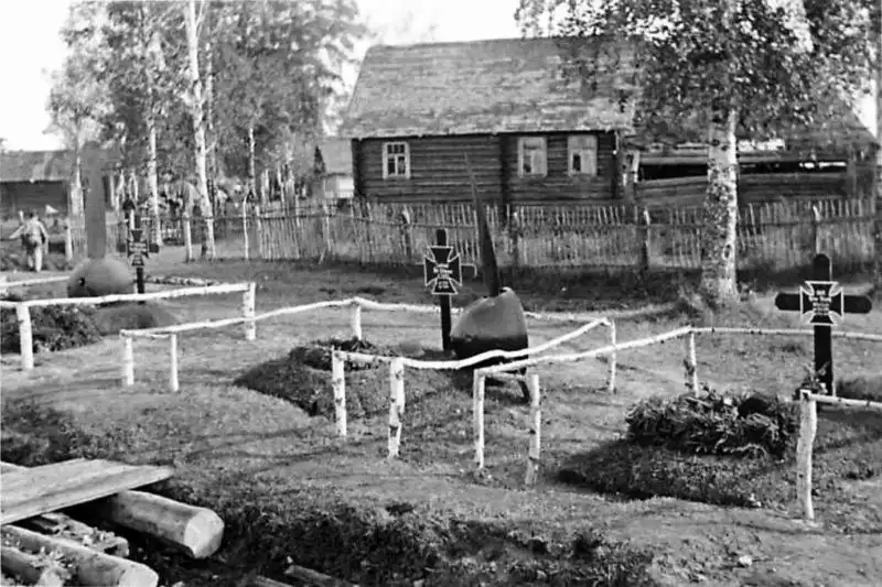 Three German military graves enclosed by a birch fence in a Soviet village, with aircraft propeller hubs and blades used as grave monuments in 1942.