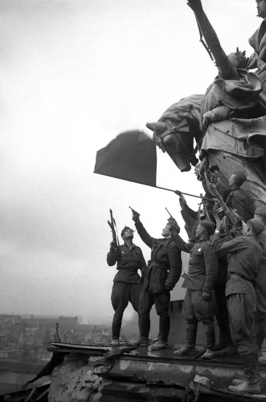 Soviet soldiers fire a joyous salute atop the Reichstag after the fall of Nazi Germany.