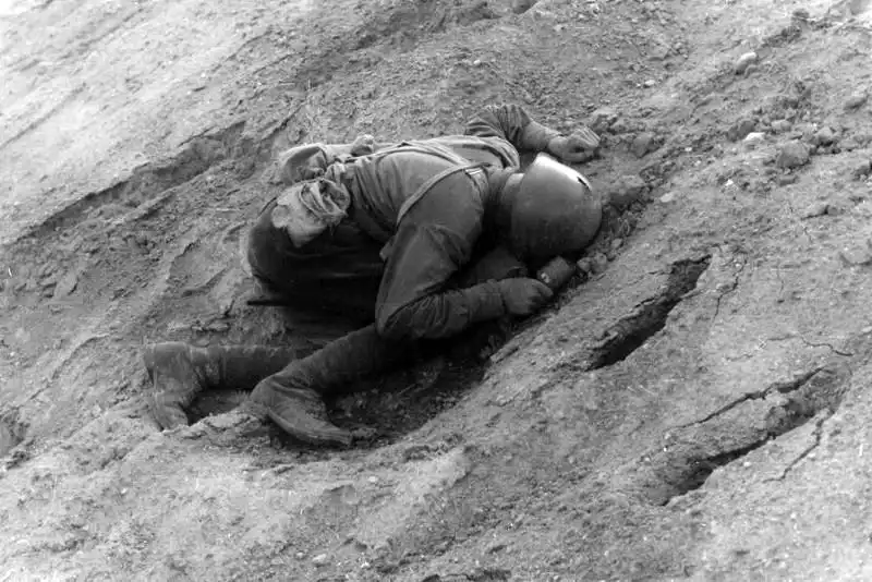 Fallen Soviet Red Army soldier in steel helmet holding an RGD-33 hand grenade with defensive sleeve in Belorussia June 1941.