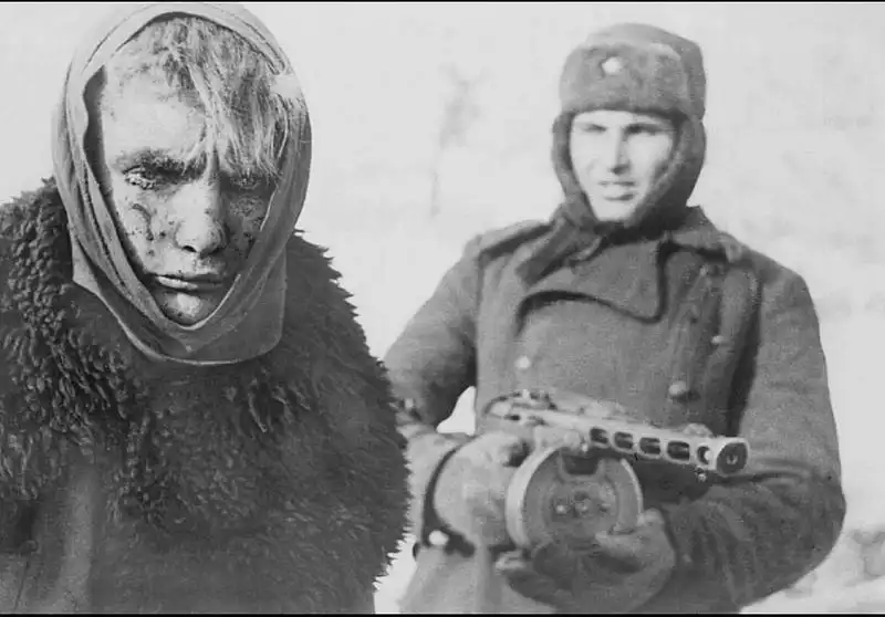 A Red Army soldier with a PPSh-41 escorting a frostbitten German prisoner wrapped in a shawl during the Battle of Stalingrad in 1943.