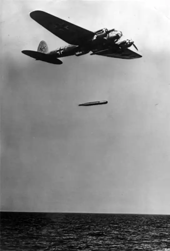 A German Heinkel He 111 torpedo bomber flying low over the sea with a dropped aerial torpedo captured mid-air above the water in October 1941.