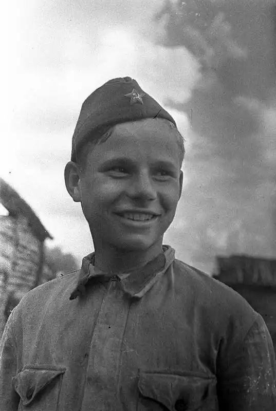 A smiling young Soviet Red Army cavalry scout in a pilotka cap and summer tunic photographed close-up by Mikhail Savin in June 1942.