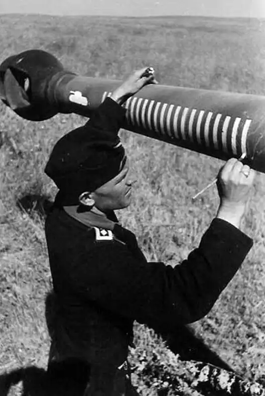 German crewman painting victory rings on the 128 mm gun barrel of a Sturer Emil self-propelled gun.
