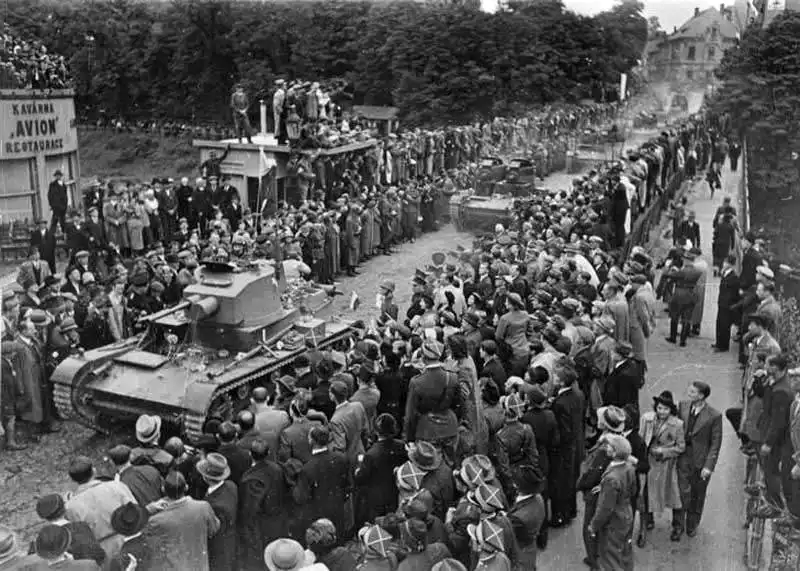 Black and white historical photo showing crowds lining a street and bridge in Cieszyn as Polish 7TP tanks advance into the city on October 2, 1938.