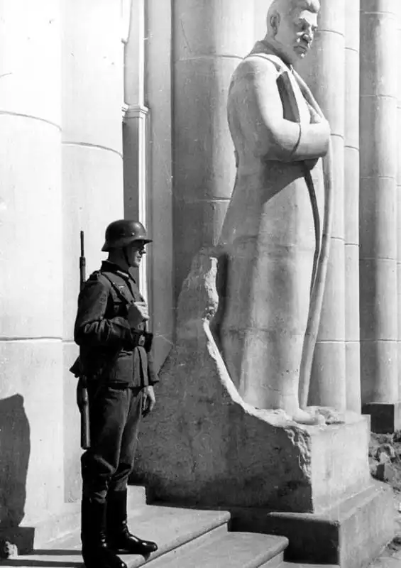 German soldier standing guard beside a Stalin statue at the former Red Army House in occupied Staraya Russa in 1941.