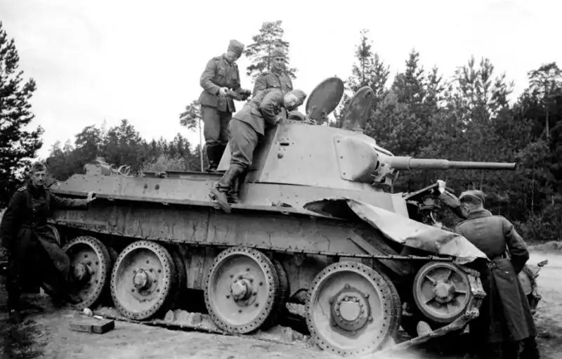 Wehrmacht soldiers inspecting a damaged Soviet BT-7 light tank abandoned by its crew during Operation Barbarossa, 1941.
