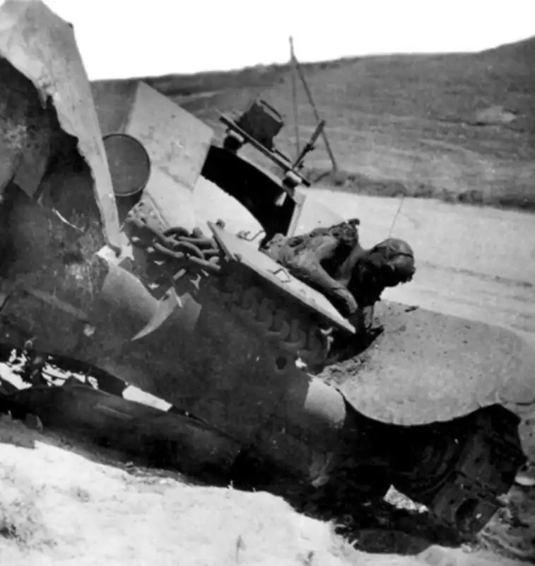 Black and white archival photograph of a destroyed Soviet BT-7 light tank with an open driver's hatch following combat in summer 1941.
