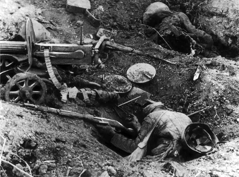 Fallen Soviet soldiers in foxhole behind a Maxim heavy machine gun and DP-27 pan magazines following mortar fire in 1942.