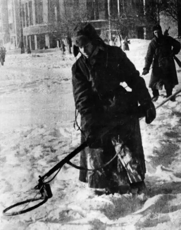 A Soviet sapper using a VIM-210 induction mine detector attached to a Mosin rifle in the snow on Nikitin Square in Voronezh, 1943.