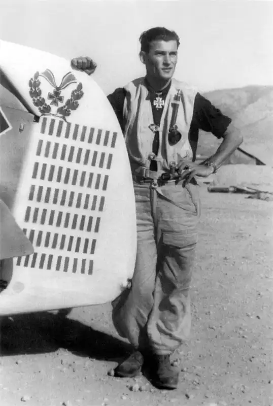 German fighter ace Heinrich Bartels posing next to the rudder of his Messerschmitt Bf 109 G-6 displaying 70 victory markings at Kalamaki airfield in Greece.