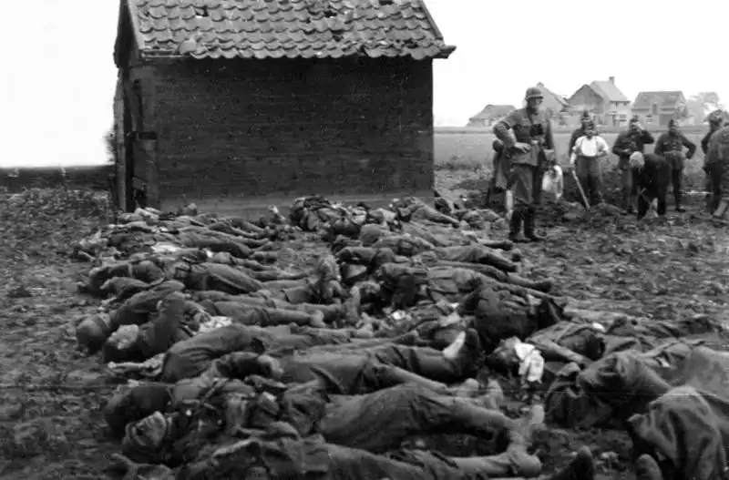 Wehrmacht infantry casualties laid out on the ground with surviving German soldiers digging a mass grave 1944.