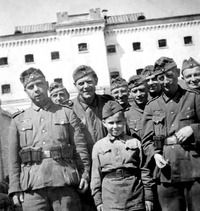 Russian child Vanya Zamotaev in Soviet uniform surrounded by German soldiers, Gemfurth, 1943.