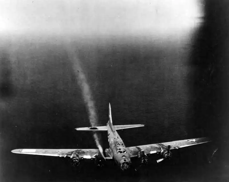 Damaged B-17F Flying Fortress trailing white smoke while returning to Great Britain after a mission over Norway in 1944.