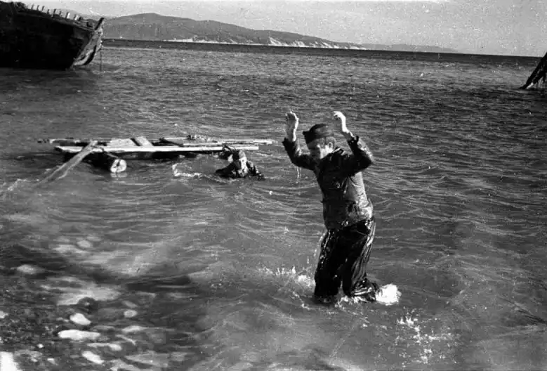 Black and white historical photo by Evgenii Khaldei showing a German soldier walking out of the Black Sea with raised hands near Novorossiysk in 1943.