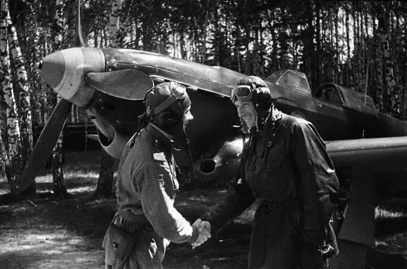 Soviet fighter pilot Semyon Sibirin congratulates French ace Albert Littolf after an aerial victory, with a Yak-1B of the Normandie squadron in the background, USSR, June 1943