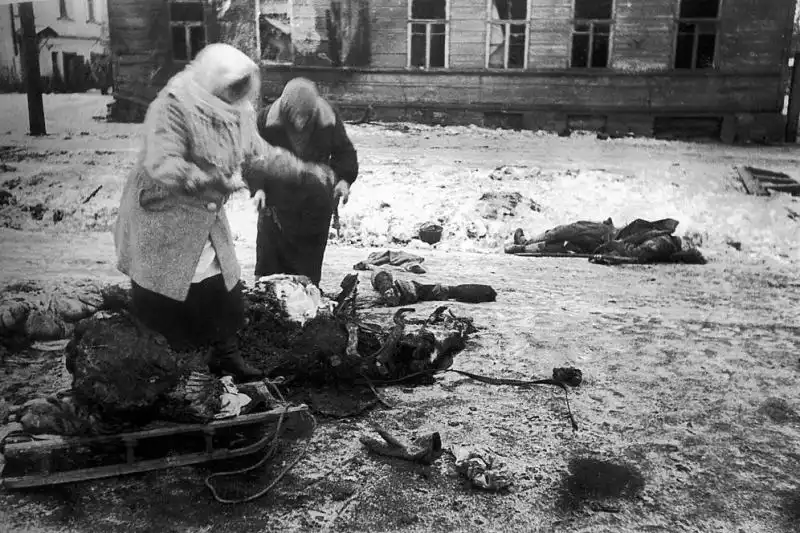 Civilians in besieged Leningrad butcher a horse killed by artillery on a city street during the winter of 1941, with the body of its Red Army driver lying nearby