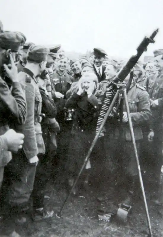 German woman covering her ears near an MG 08/15 light machine gun on an anti-aircraft tripod surrounded by laughing Wehrmacht soldiers Poland 1939.