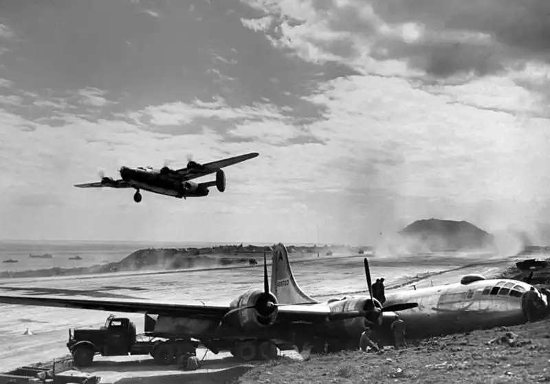 USAAF B-29 Superfortress bomber serial 44-69703 resting on its belly alongside a Federal 604 tractor truck on Iwo Jima in March 1945.
