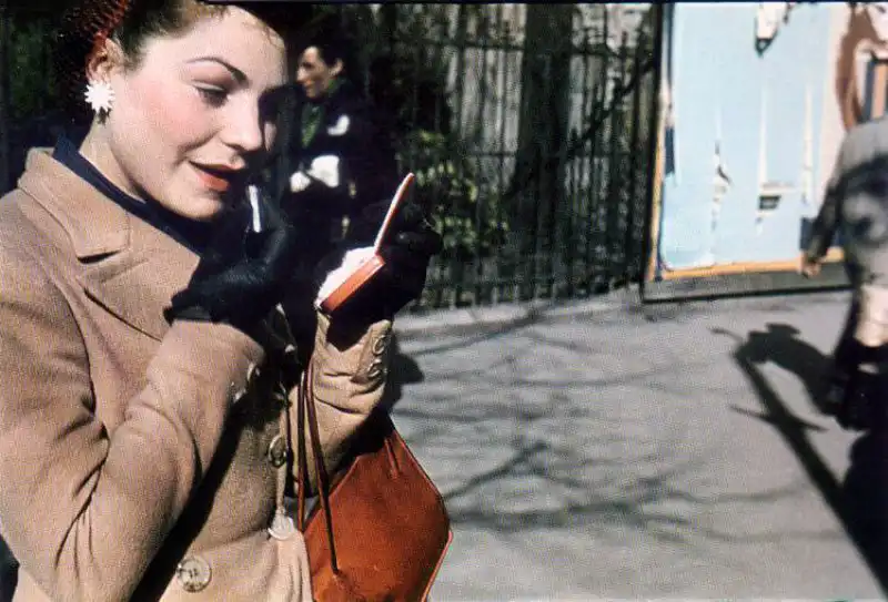 Young Parisian woman applying lipstick beside the Seine River during the German occupation of Paris, 1943 color WWII photograph