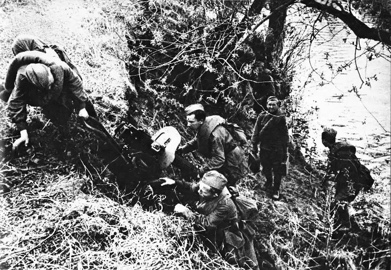 Soviet Maxim machine gun crew hauling heavy weapon across a steep riverbank during the August 1945 offensive against Japan