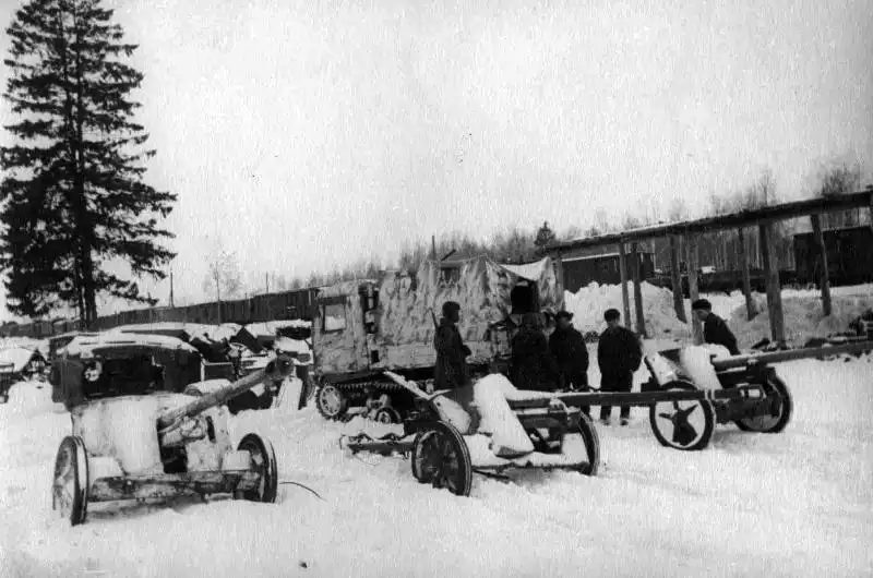 Soviet soldiers inspecting captured German 5 cm PaK 38 anti-tank guns with a whitewashed STZ-5 artillery tractor in the background, winter 1941