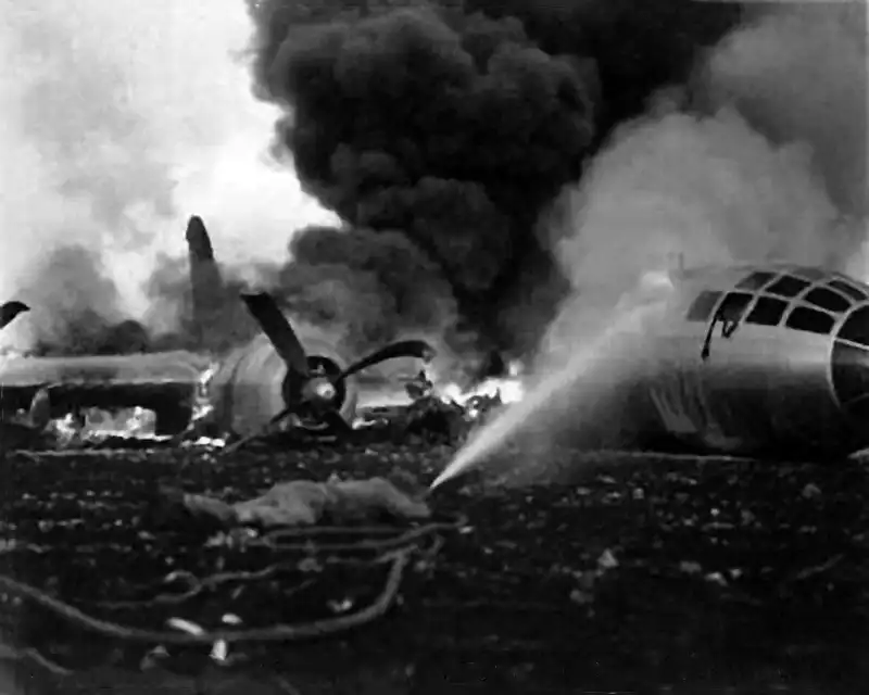 Burning wreckage of Boeing B-29 Superfortress Queen Cathy with firefighters on Guam airbase after a crash landing in May 1945.