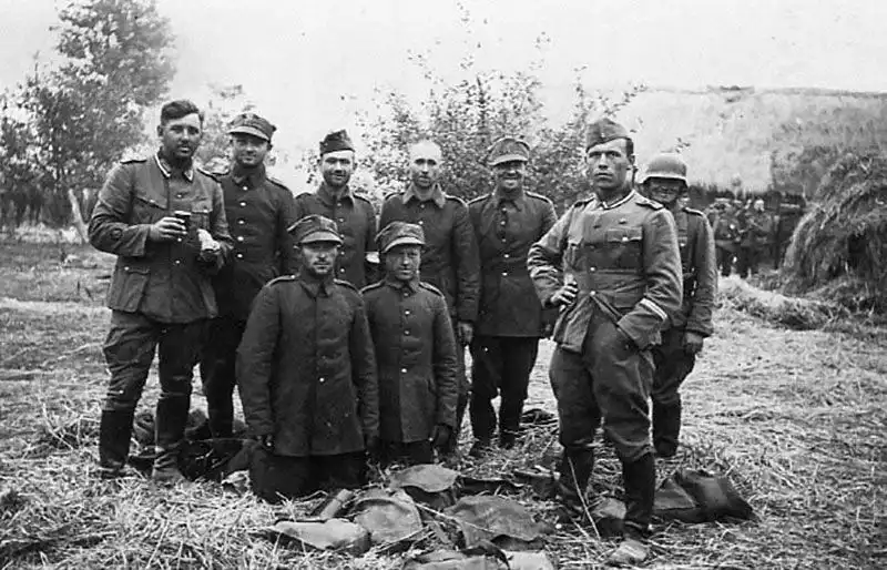 German Hauptfeldwebel with double sleeve chevrons standing alongside captured Polish soldiers surrounded by discarded equipment and breadbags near Lviv in September 1939.