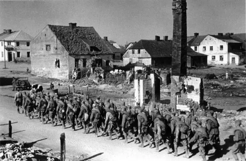 Column of Soviet infantrymen carrying equipment marching through a damaged town on the 3rd Belorussian Front in August 1944.