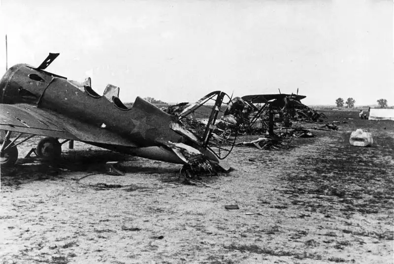 Destroyed Soviet UTI-4 and I-16 wrecks at a captured airfield in Latvian SSR, with a German Henschel Hs-126 in the background, taken during summer 1941.
