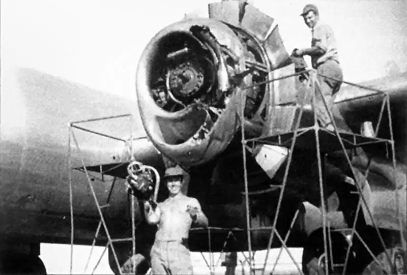 American mechanics repairing the damaged engine of a B-29 Superfortress on a Pacific island airfield during World War II.