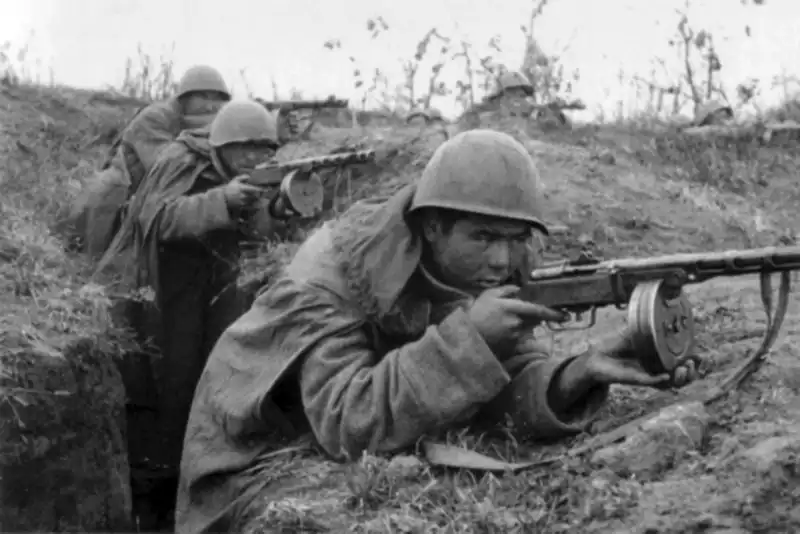 Red Army submachine gunner taking aim with a PPSh-41 submachine gun from a trench line in 1942.
